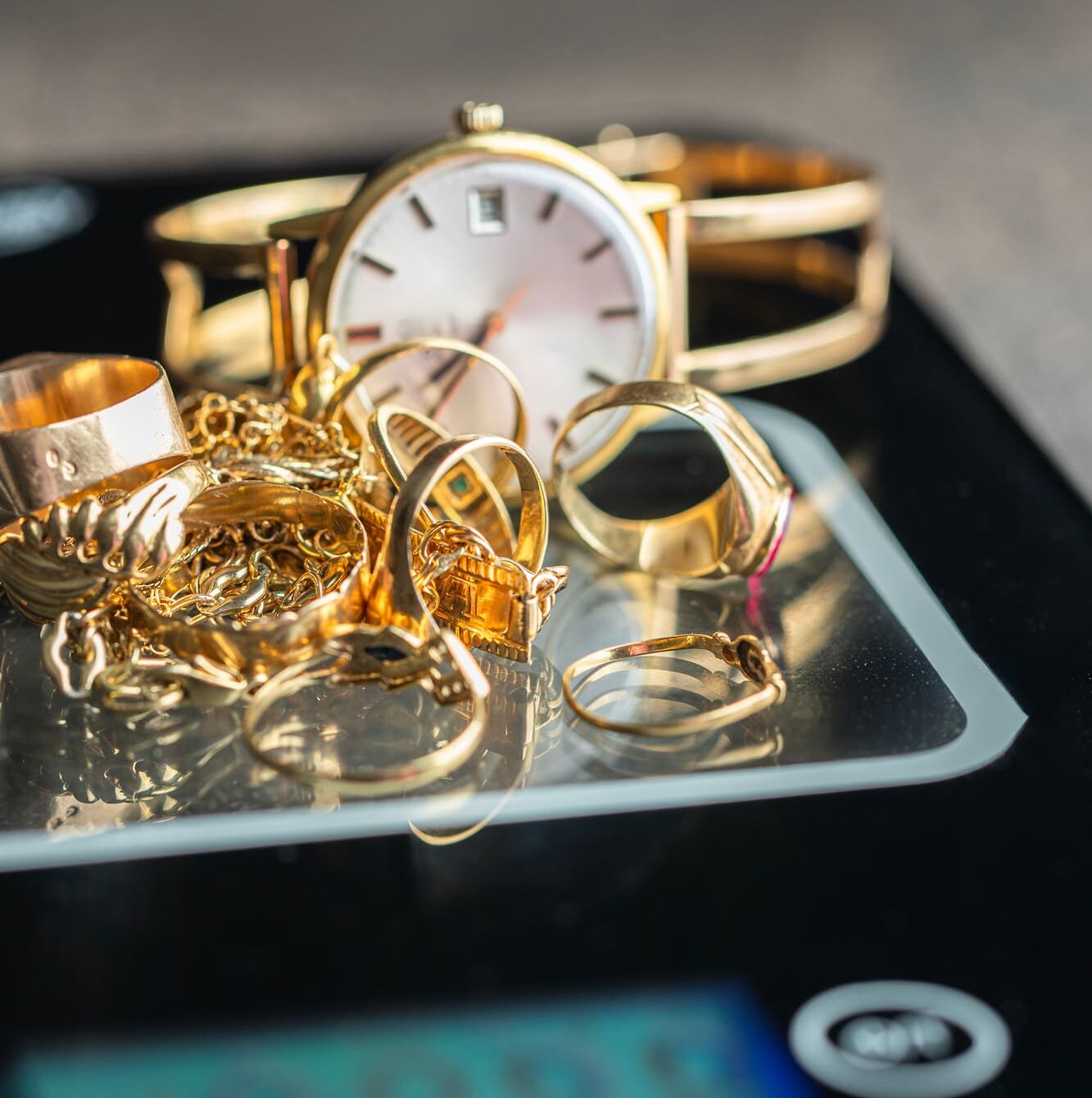 Des bagues en or, des chaînes et une montre sur une balance certifiée représentent le concept de la vente d'or contre de l'argent comptant, de l'estimation et de l'évaluation de bijoux.